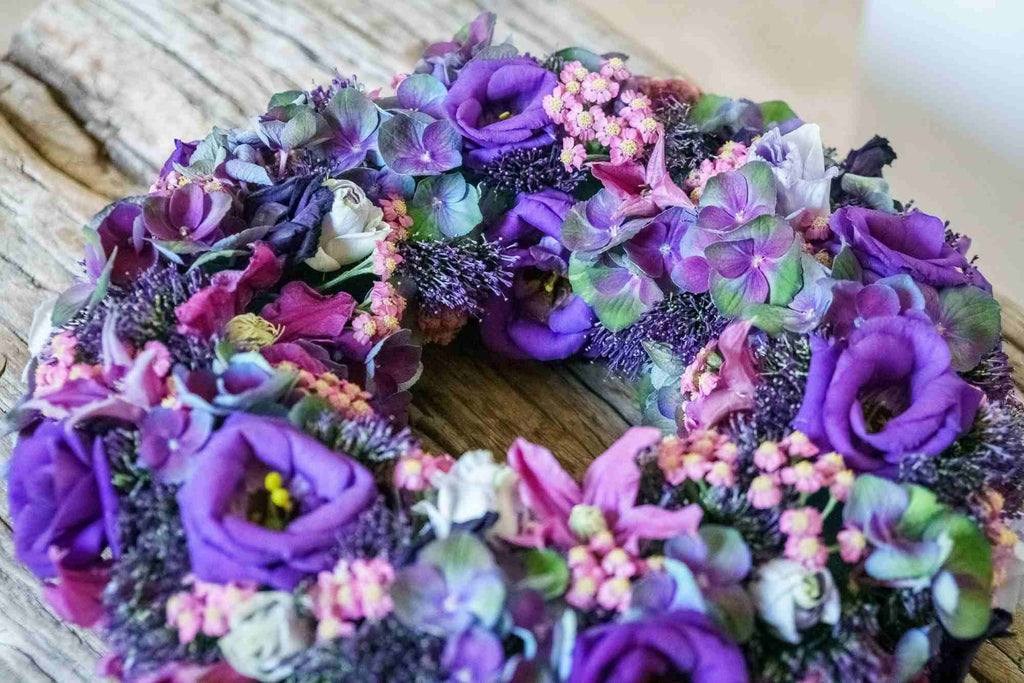 Blumengesteck : Blumenkranz in Violettöne, Kreation von fleurs-devie.ch – couronne de fleurs dans les tons violets, création de fleurs-devie.ch